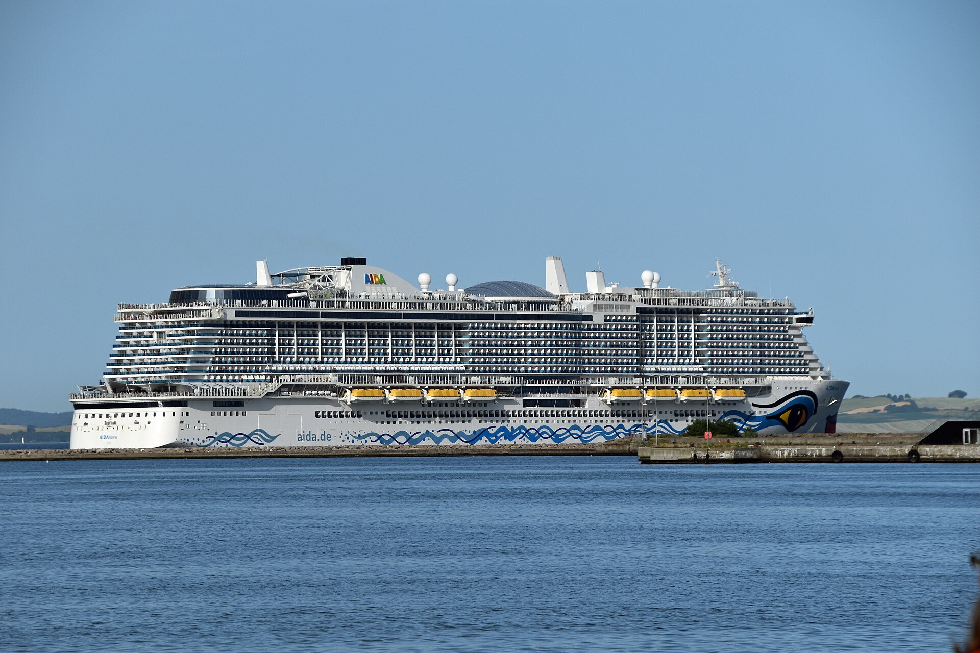 AIDAnova beim Auslaufen aus Aarhus. Foto: Tdn70; Quelle: Wikimedia Commons, https://commons.wikimedia.org/wiki/File:AIDAnova_(ship%2C_2018)_leaving_Aarhus_Havn.jpg; Lizenz: CC BY 4.0, https://creativecommons.org/licenses/by/4.0/
